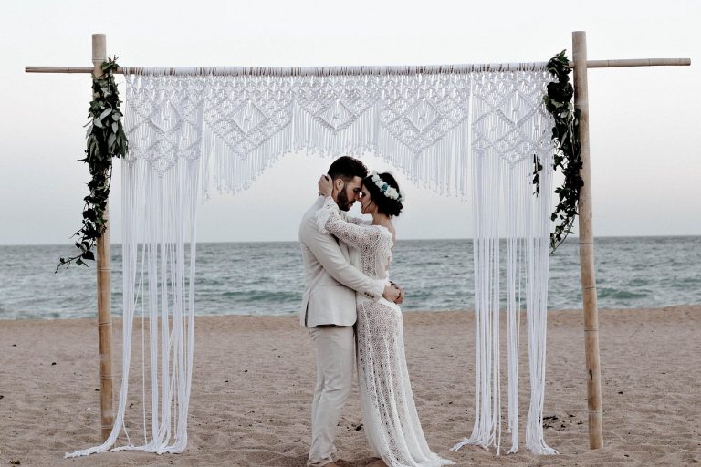Organiser un mariage intimiste peut ressembler à ce genre de photo. Un couple devant une belle arche au bord de l'eau. Peu d'invités et un cadre très romantique.